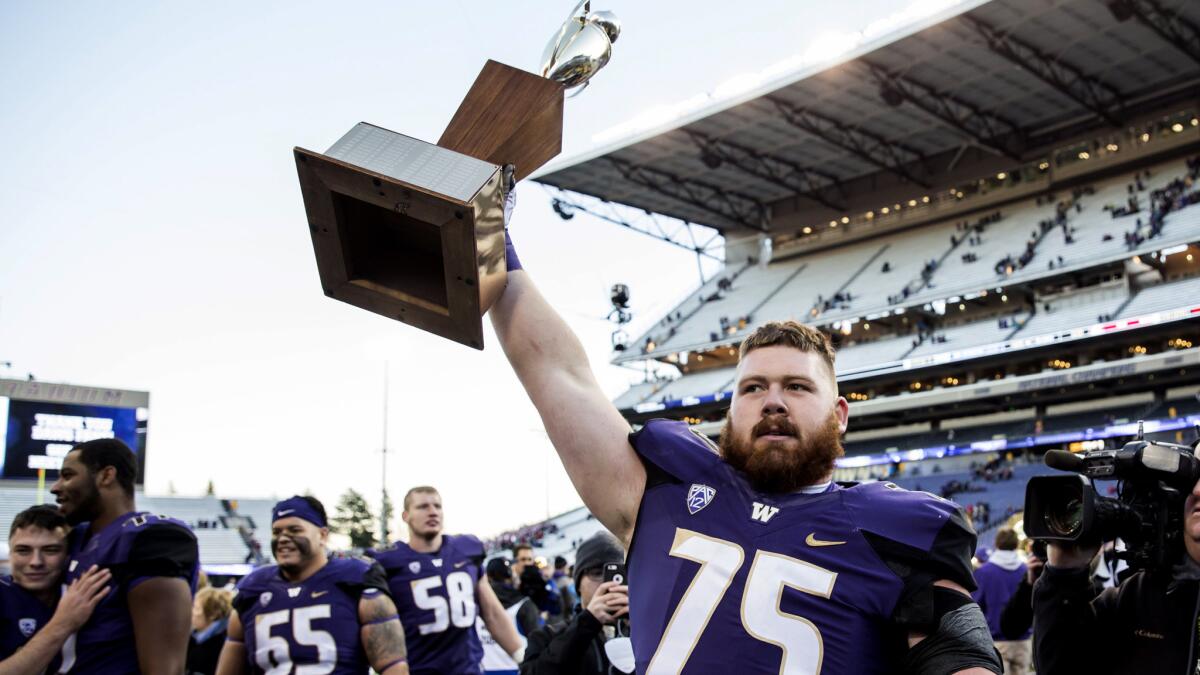 Washington offensive lineman Jesse Sosebee holds aloft the Apple Cup after the Huskies defeated Washington State on Friday.