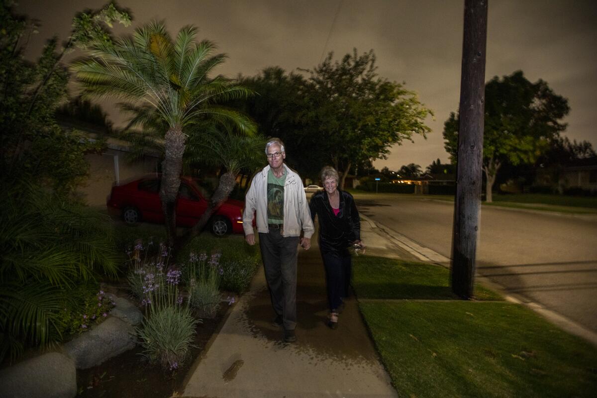 Nurse Penny Weismuller and her husband, Tom, hold hands while walking in their neighborhood in Orange.