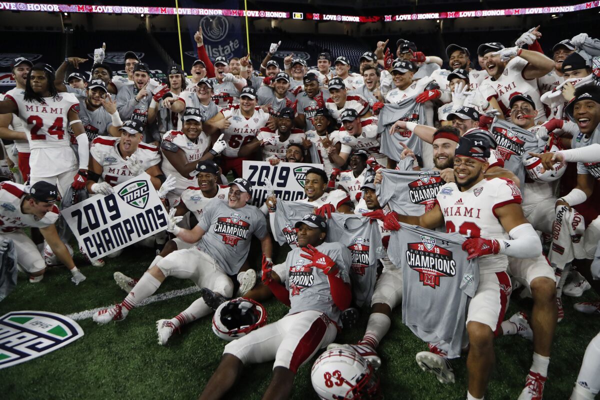 FILE - In this Dec. 7, 2019, file photo, members of the Miami of Ohio team pose on the field after the Mid-American Conference championship NCAA college football game against Central Michigan, in Detroit. The Mid-American Conference on Saturday, Aug. 8, 2020, became the first league competing at college football’s highest level to cancel its fall season because of COVID-19 concerns. A person with knowledge of the decision told The Associated Press the university president’s voted to not play in the fall and consider a spring season. The person spoke to AP on condition of anonymity because an official announcement was still being prepared.(AP Photo/Carlos Osorio, File)