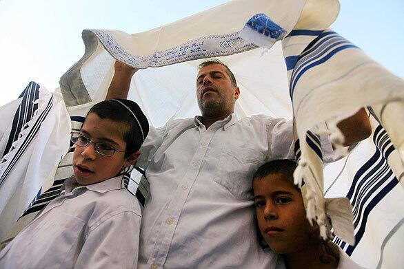 A Jewish man and his children covered with a tallit (a prayer shawl) attend the Cohanim prayer (priest's blessing) at the annual celebration of Sukkot, or the Feast of the Tabernacles. Thousands of Jews make the pilgrimage to Jerusalem during Sukkot, which commemorates the desert wanderings of the Israelites after their exodus from Egypt.