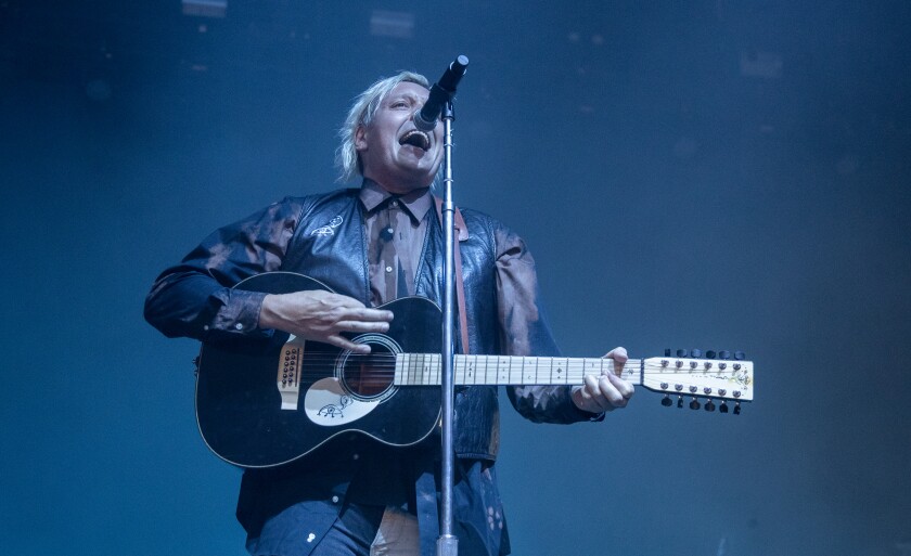 A man sings and plays acoustic guitar onstage.