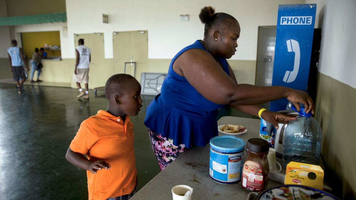 Jelisa Laws prepares breakfast for her son at a shelter at the Sir Vivian Richards cricket stadium near St. John's, Antigua.