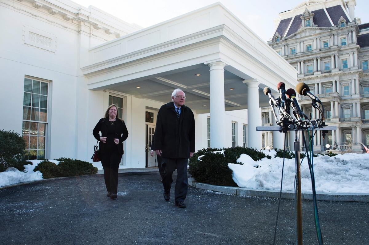 Democratic presidential candidate Sen. Bernie Sanders walks with his wife, Jane O'Meara Sanders, to speak to reporters after meeting with President Obama at the White House on Wednesday.