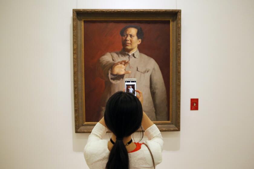 A visitor snaps a photo of a painting of former Chinese leader Mao Zedong during an exhibition of works to celebrate the anniversary of the founding of the Communist Party at the National Museum of China in Beijing on June 30, 2016. The 95th anniversary of the founding is July 1.