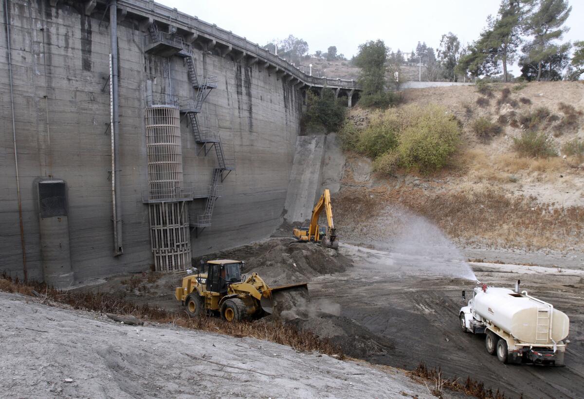 Los Angeles County Department of Public Works crews work to remove dirt from the base of Devil's Gate Dam at Hahamongna Watershed Park in Pasadena on Wednesday, Sept. 18, 2013.