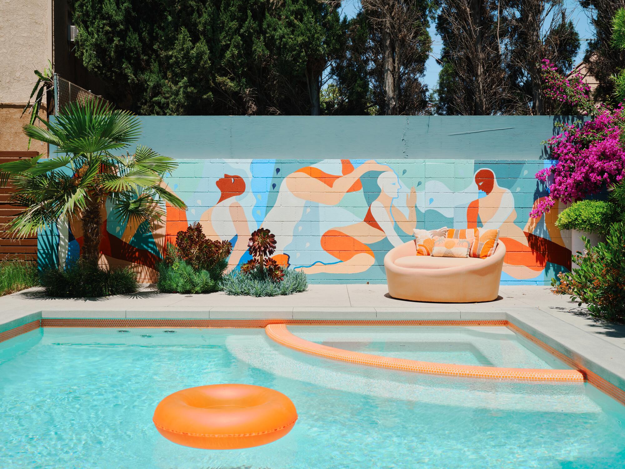 An orange inflatable ring floats in the pool in front of a mural depicting bathers dressed in orange.