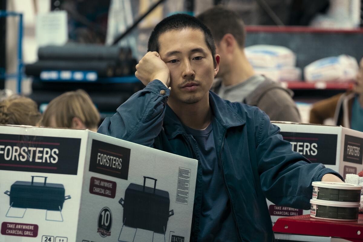 A man leans dejectedly on a picnic grill at a big box store.