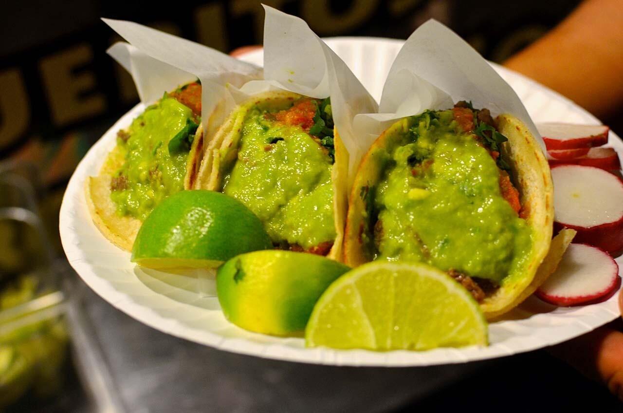 Tijuana-style tacos are wrapped up tightly and topped with a scoop of thick, smashed avocado.
