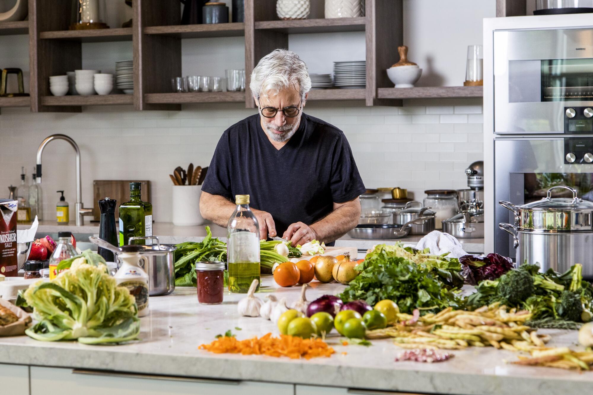 A man chops vegetables in a kitchen.