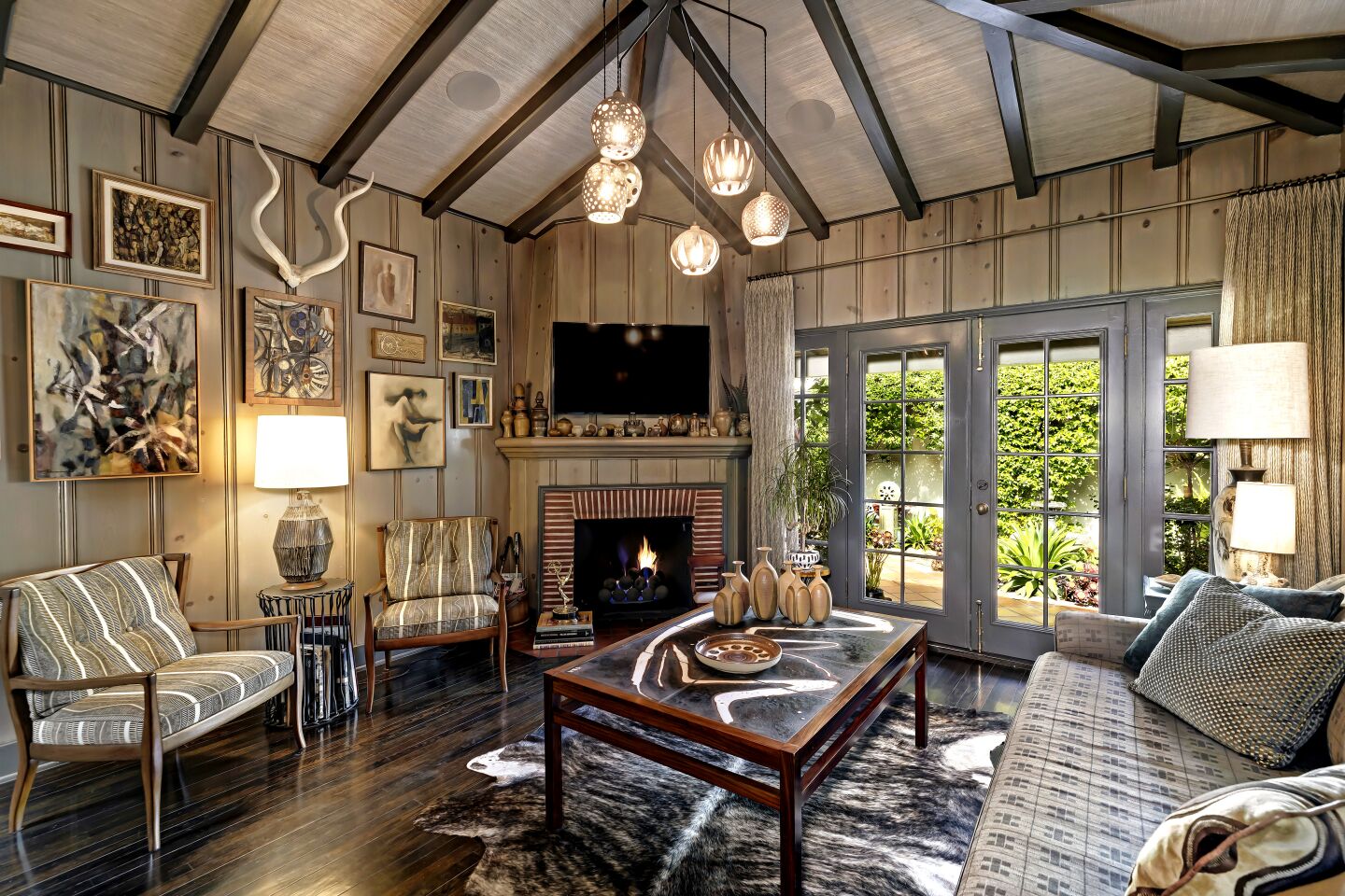 A paneled den with wood-beamed ceilings, brick fireplace and double glass doors leading outside