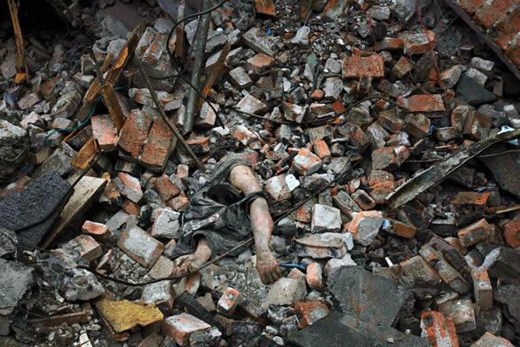 The body of a quake victim is partially buried in the rubble of a building in Dujiangyan, China.