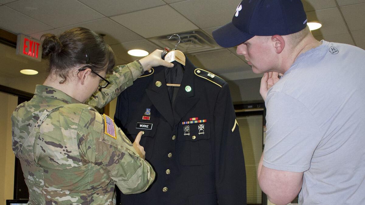 Staff Sgt. Cathrine Schmid examines a junior soldier's dress uniform. "She’s been a blessing,” said one noncommissioned officer. “I wish I had more like her.”