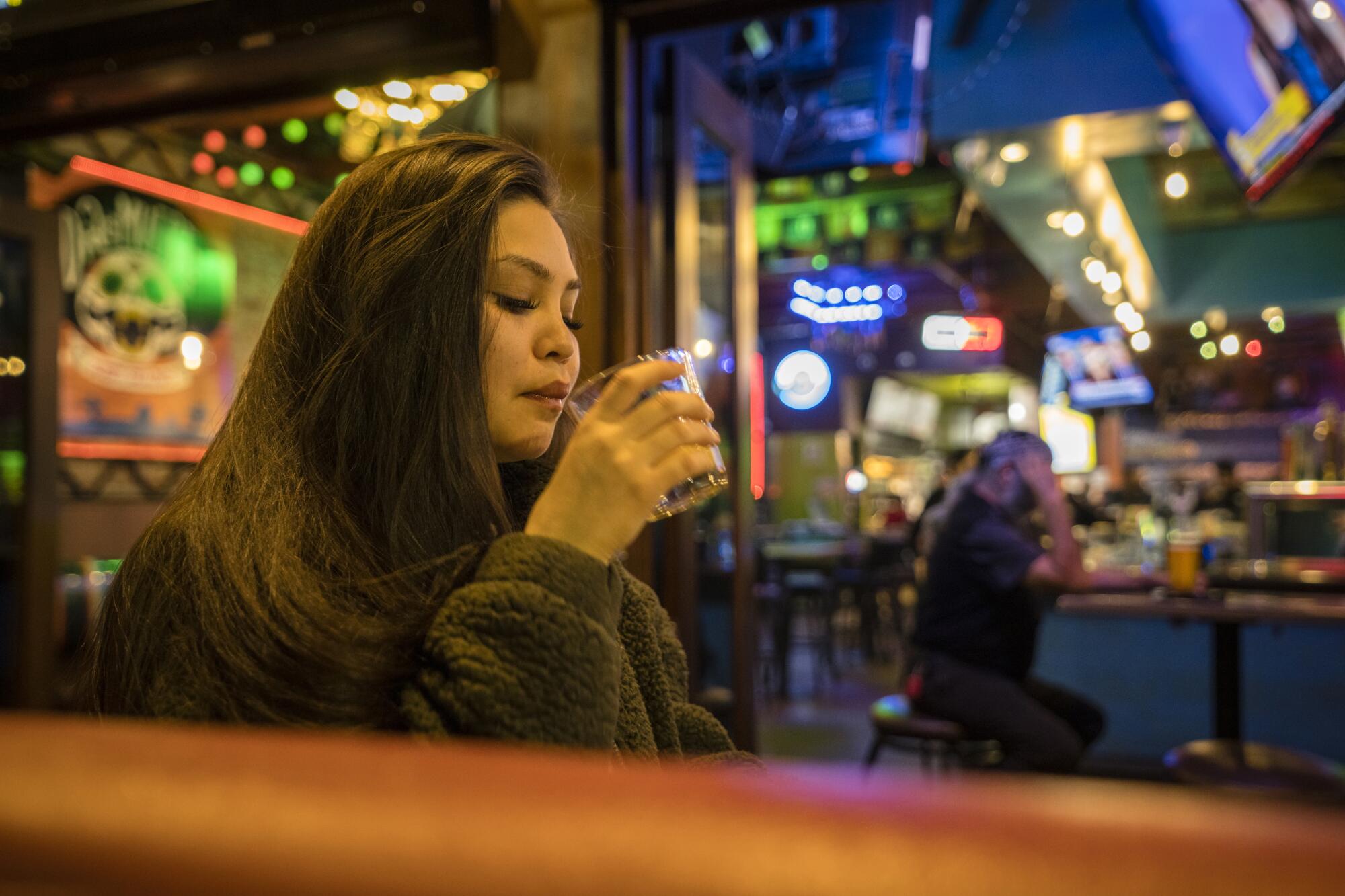 A woman drinks outside a bar