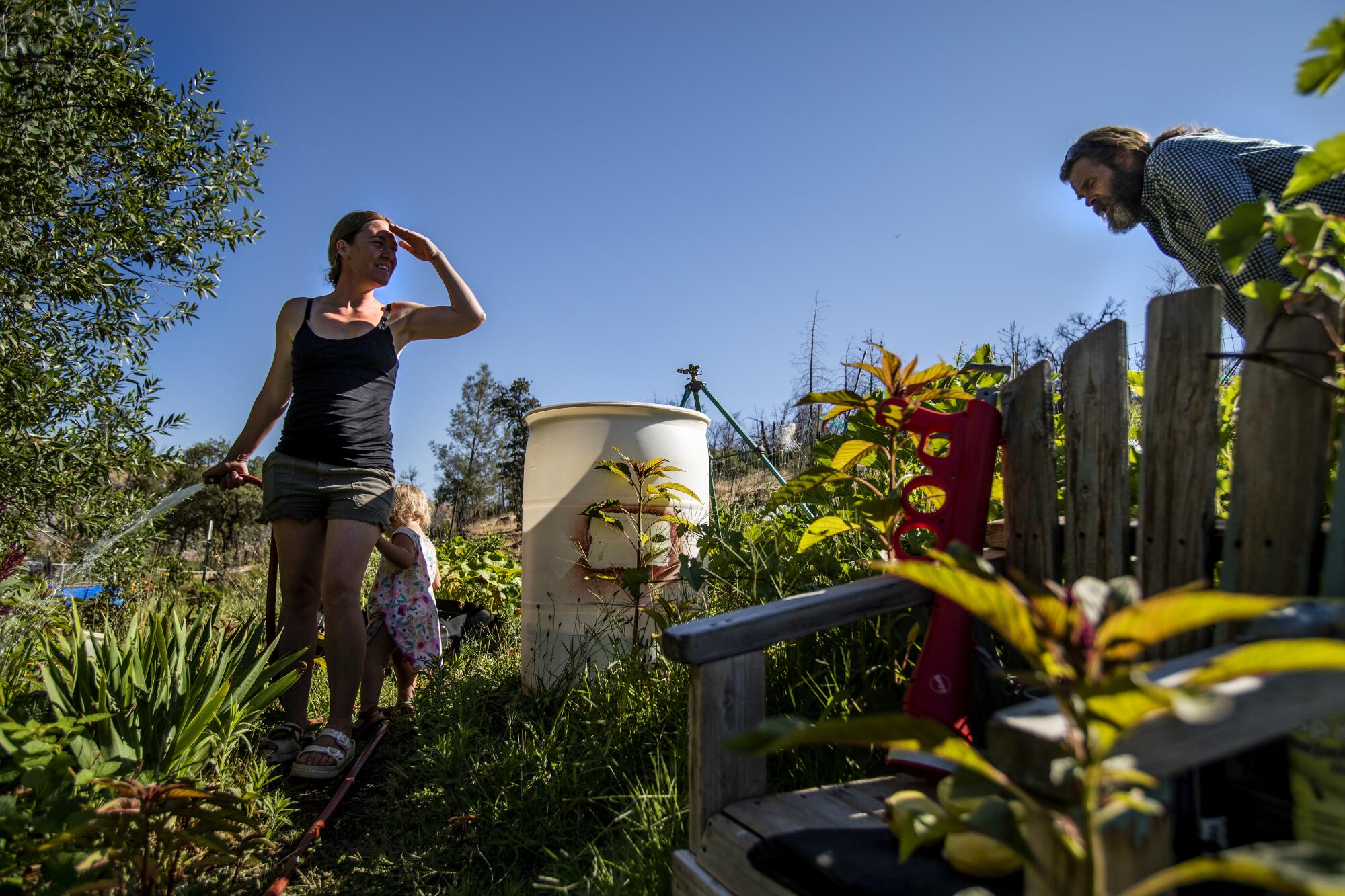Lacey Nimz, with her young daughter at her side, waters while Mike Nimz bends, inspecting plants.