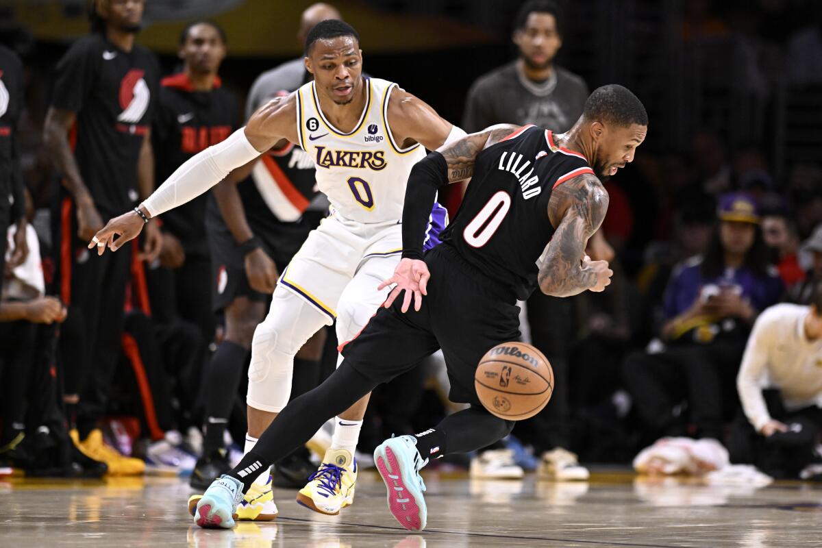 Portland Trail Blazers guard Damian Lillard loses the ball in front of Lakers guard Russell Westbrook.