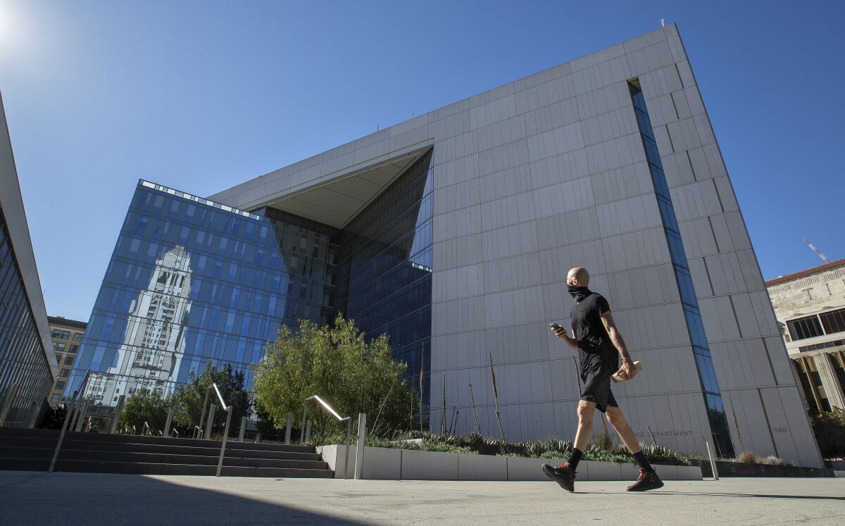 A masked pedestrian walks in front of LAPD headquarters in downtown Los Angeles.