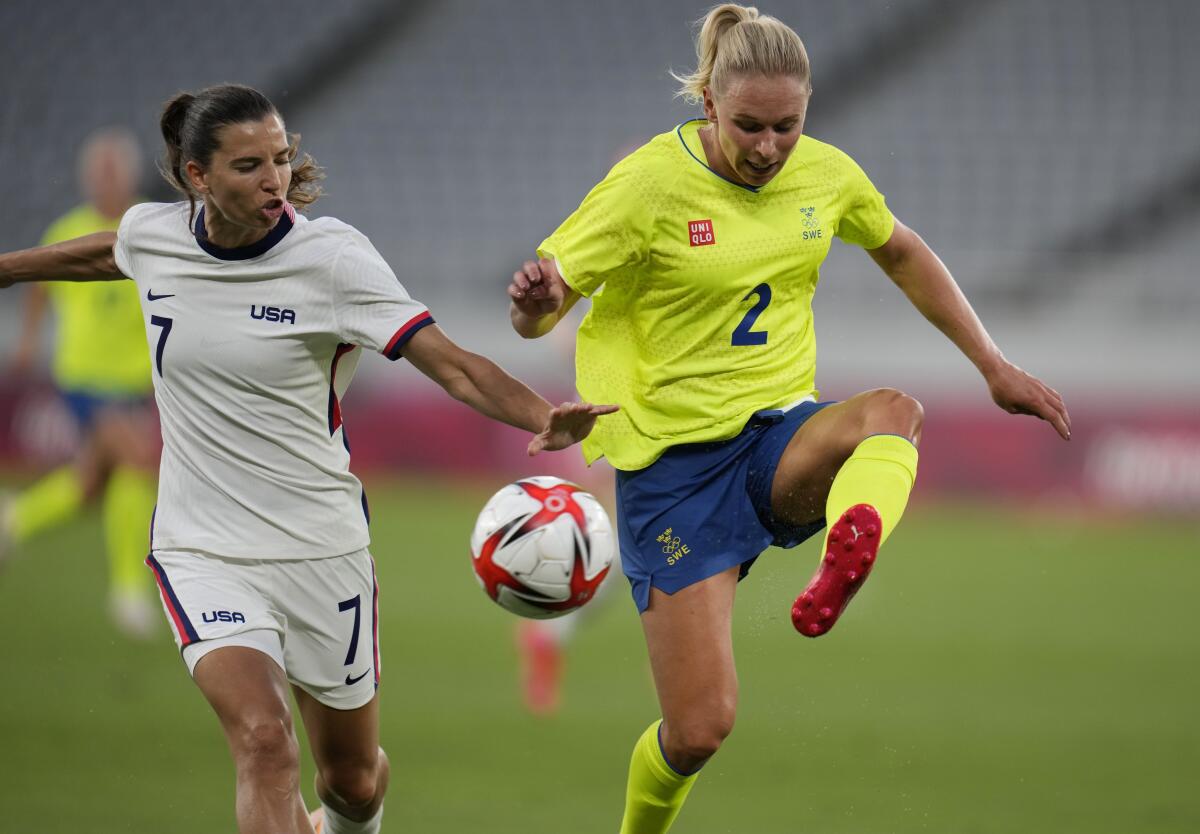 Two women vie for a soccer ball as they run.