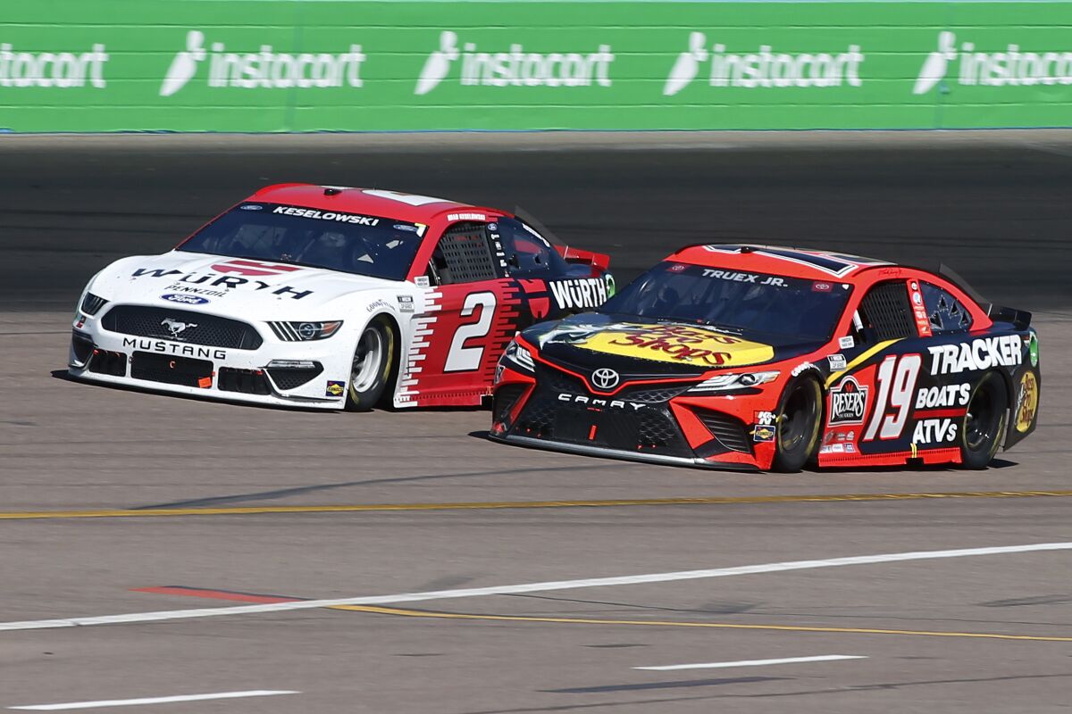 Martin Truex Jr (19) and Brad Keselowski (2) race out of Turn 2 during a NASCAR Cup Series auto race.