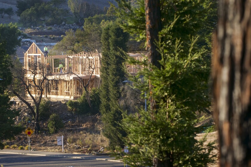 FILE - In this Tuesday, Nov. 5, 2019, file photo, builders work on a new home in Santa Rosa, Calif. California state and local officials are incentivizing rebuilding in areas destroyed by wildfires at a time when people should be redirected away from those areas if the state wants to reduce the economic and human impact of increasingly destructive wildfires, according to a report published Thursday, June 10, 2021. (AP Photo/Lacy Atkins, File)