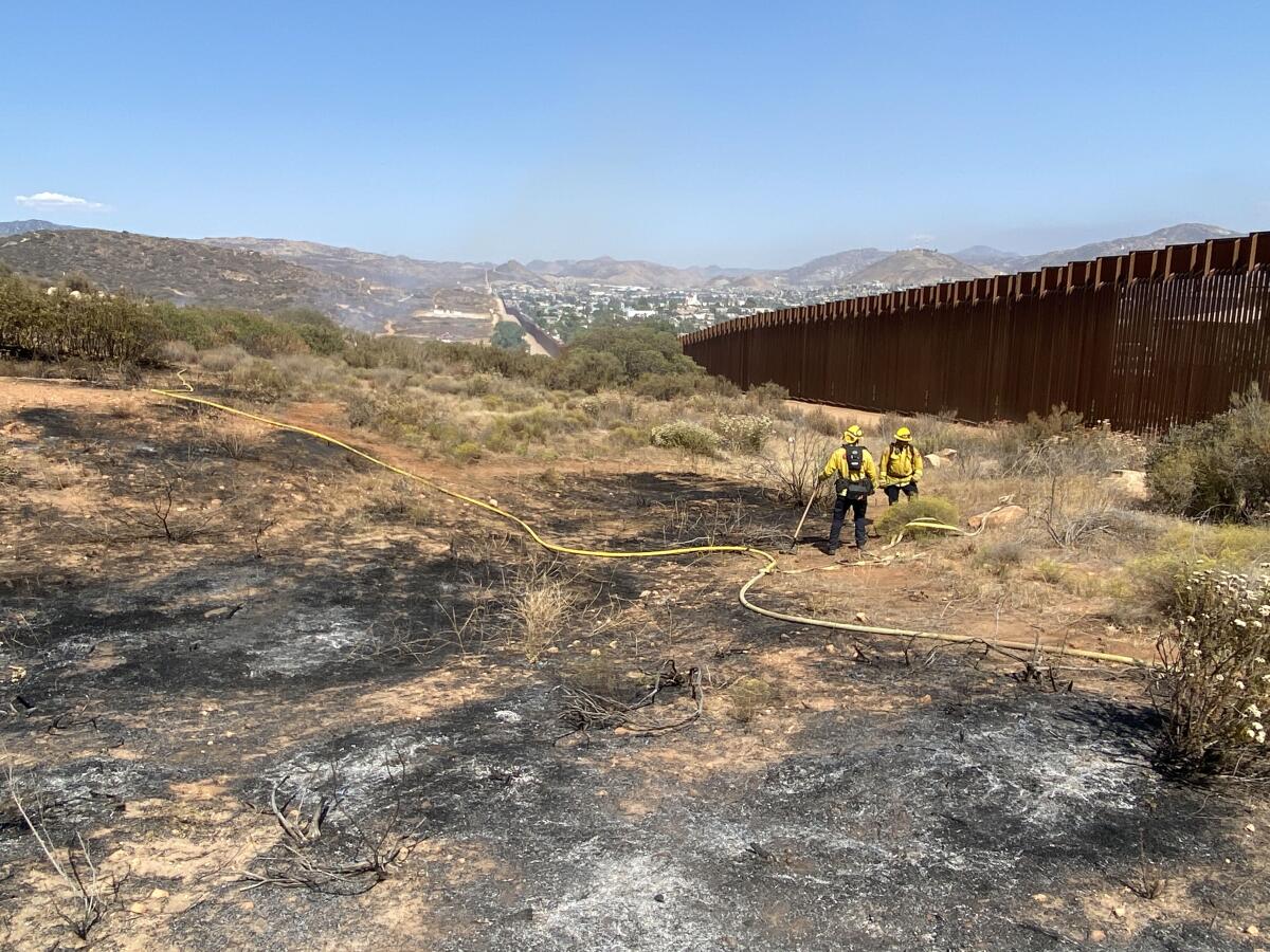 Cal Fire San Diego firefighters deal with a brushfire Thursday afternoon near the Tecate Port of Entry.