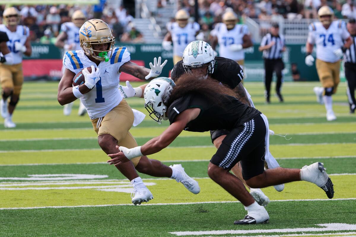 UCLA's Rico Flores Jr. stiff-arms Hawaii's Peter Manuma during the Bruins' win 