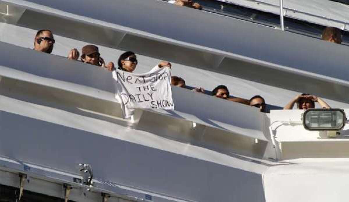 A passenger aboard the Carnival Splendor waves a T-shirt message as the cruise ship is tied up in San Diego Harbor in 2010.