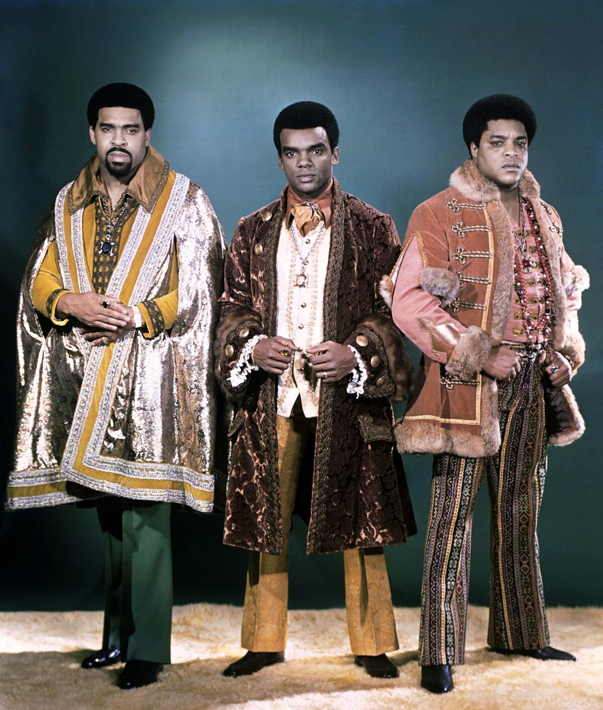 Three singers in long coats in the 1970s