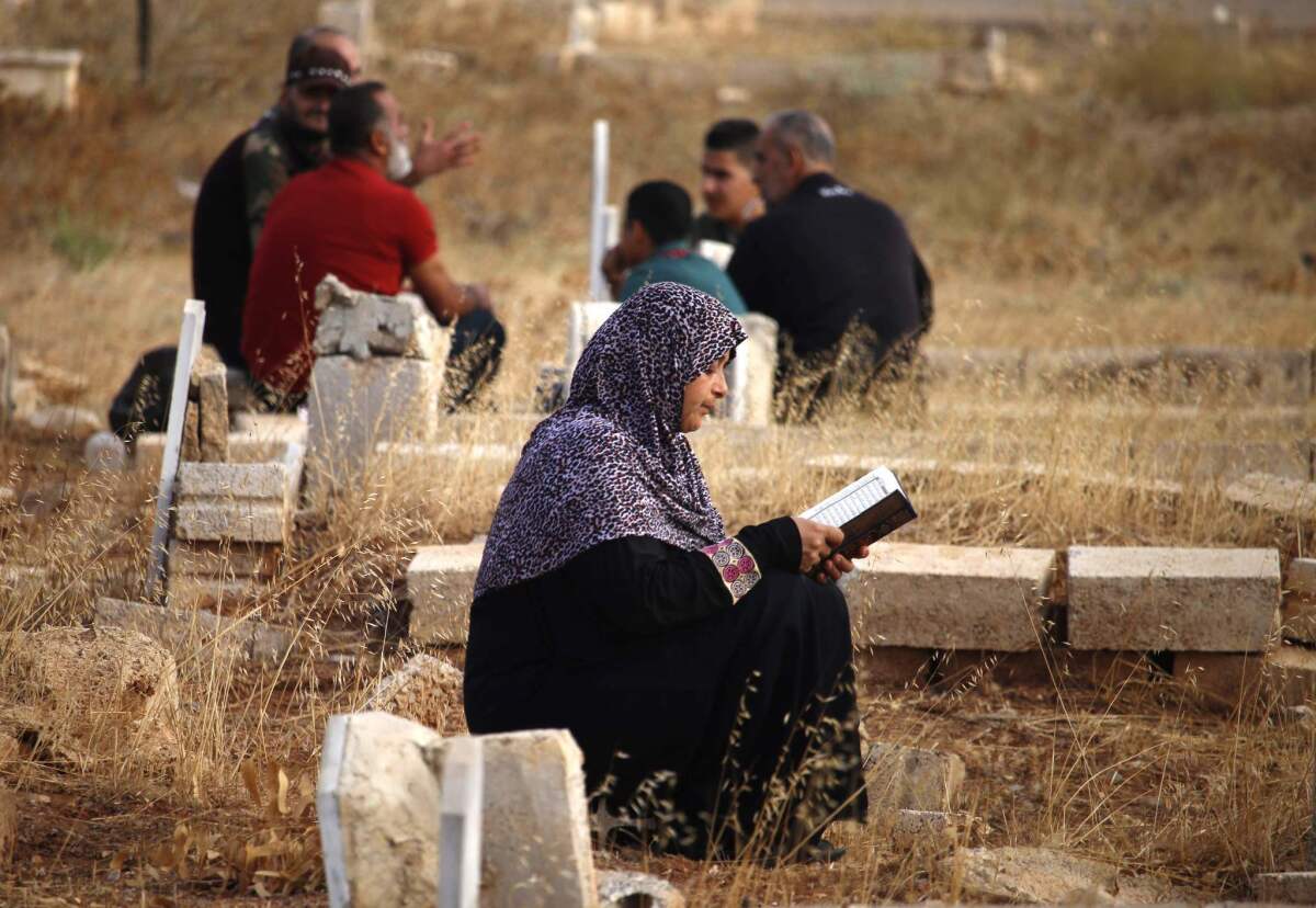 Syria: A woman reads the Koran near a relative's tomb in the opposition-held southern city of Dara on the first day of Eid al-Adha.