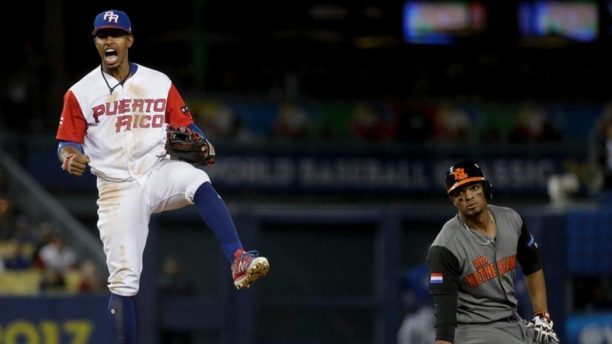 Puerto Rico shortstop Francisco Lindor, left, celebrates after forcing Netherlands' Xander Bogaerts out at second on a double play in a semifinal of the World Baseball Classic on March 20.