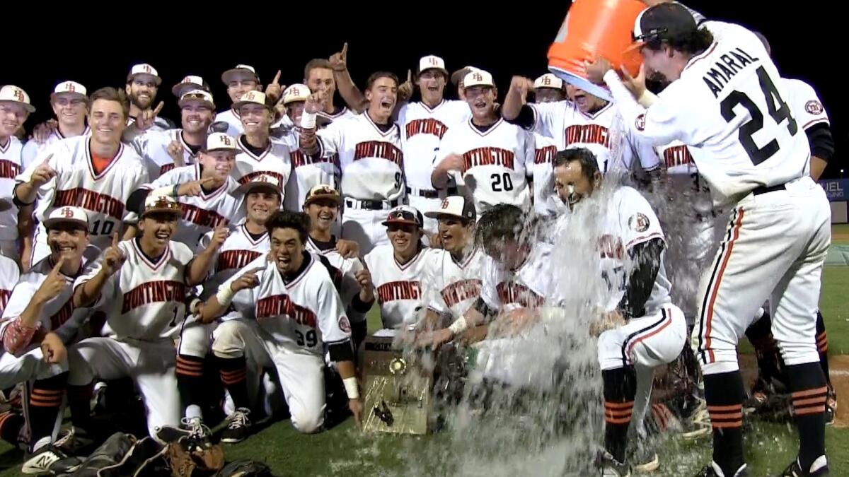 Huntington Beach High baseball Coach Benji Medure gets soaked as the team poses for a photo following their victory in the Southern Section Division 1 championship last season.