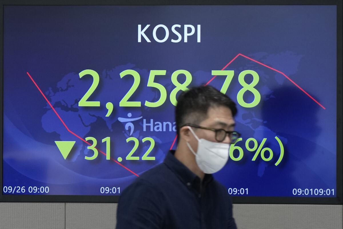 A currency trader walks near a screen showing the Korea Composite Stock Price Index