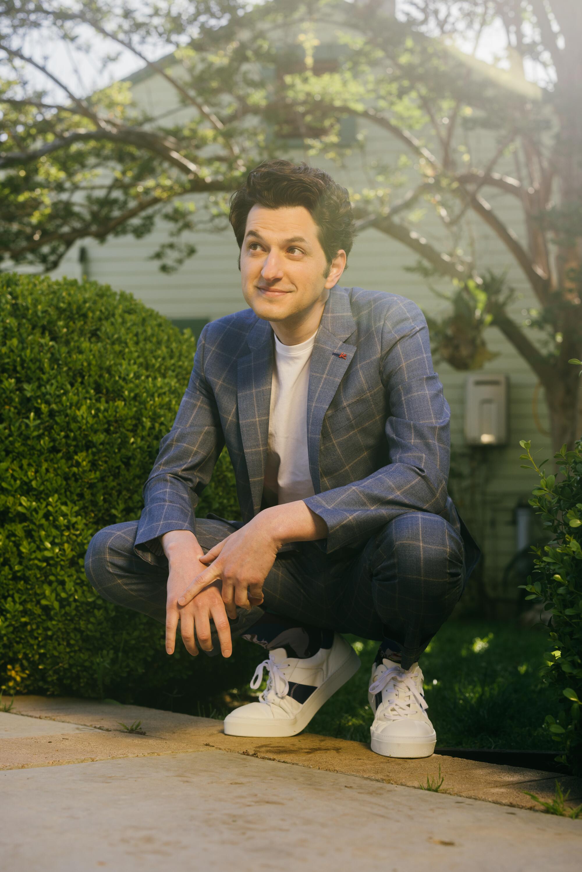Ben Schwartz bends down in front of a bush at a private residence.