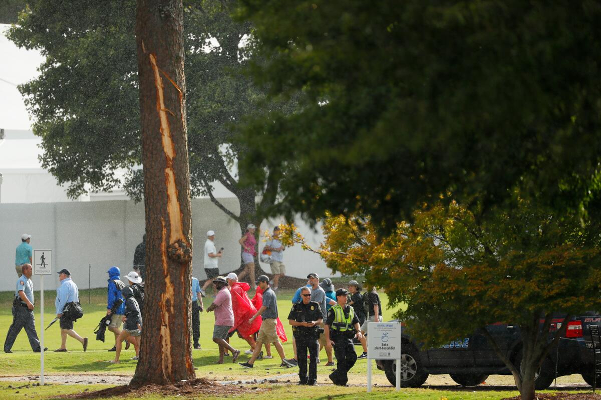 ATLANTA, GEORGIA - AUGUST 24: Police officers stand watch next to a tree damaged by a lightning strike during a suspension in play of the third round of the TOUR Championship at East Lake Golf Club on August 24, 2019 in Atlanta, Georgia. (Photo by Kevin C. Cox/Getty Images) ** OUTS - ELSENT, FPG, CM - OUTS * NM, PH, VA if sourced by CT, LA or MoD **
