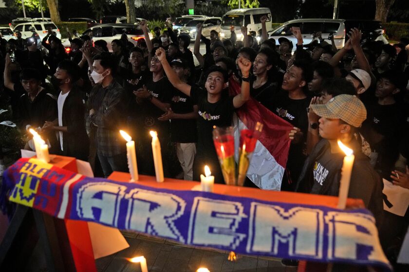 Soccer fans chant slogans during a candle light vigil for Arema FC Supporters who became victims of Saturday's soccer riots, outside the Youth and Sports Ministry in Jakarta, Indonesia, Sunday, Oct. 2, 2022. Panic and a chaotic run for exits after police fired tear gas at a soccer match between Arema FC and Persebaya in East Java to drive away fans upset with their team's loss left a large number of people dead, most of whom were trampled upon or suffocated. (AP Photo/Dita Alangkara)