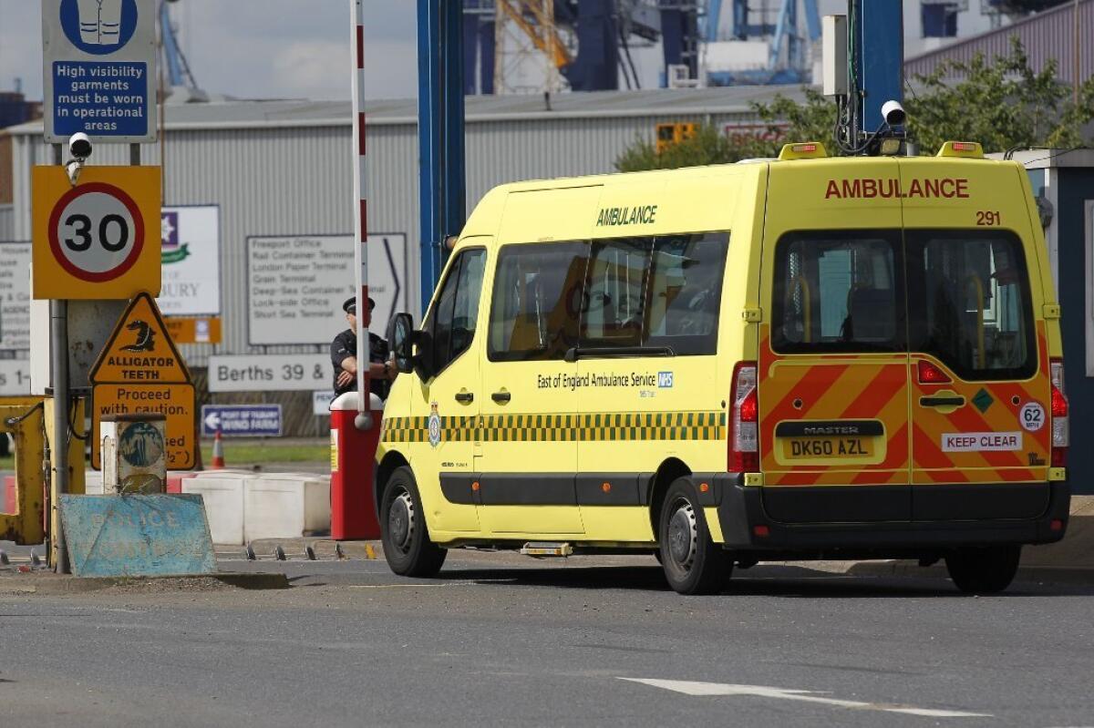 An ambulance arrives at the entrance to the Port of Tilbury near London, where one man was found dead and 34 others were hospitalized Saturday after they were discovered inside a shipping container.