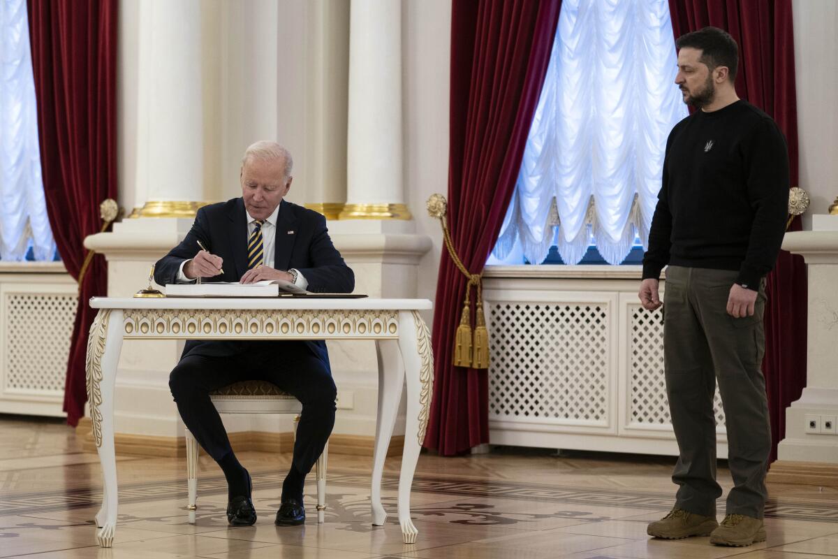El presidente ucraniano Volodymyr Zelenskyy observa mientras el mandatario estadounidense Joe Biden firma 