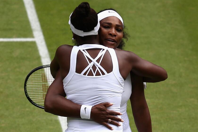 Sisters Serena, right, and Venus Williams embrace Monday after their match at Wimbledon.