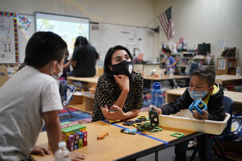 Teacher Juliana Urtubey, center, works with Brian Avilas, left, and Jesus Calderon Lopez, right, in a class at Kermit R Booker Sr Elementary School Wednesday, May 5, 2021, in Las Vegas. Urtubey is the the 2021 National Teacher of the Year. (AP Photo/John Locher)