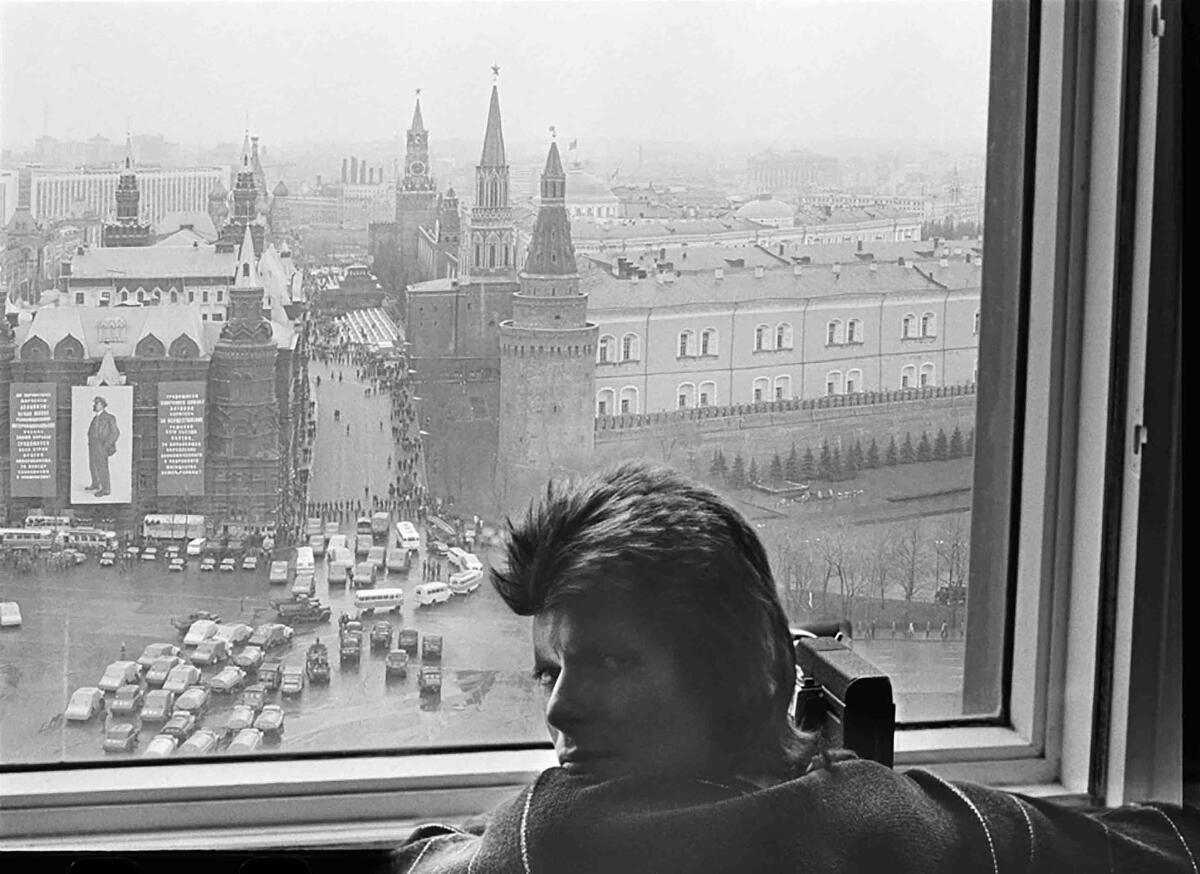 A man looks out a hotel room window in Moscow.