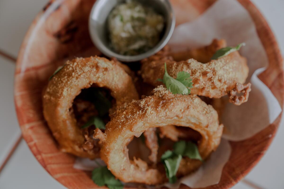 A bowl of thick-cut onion rings in a fluffy, fried batter.
