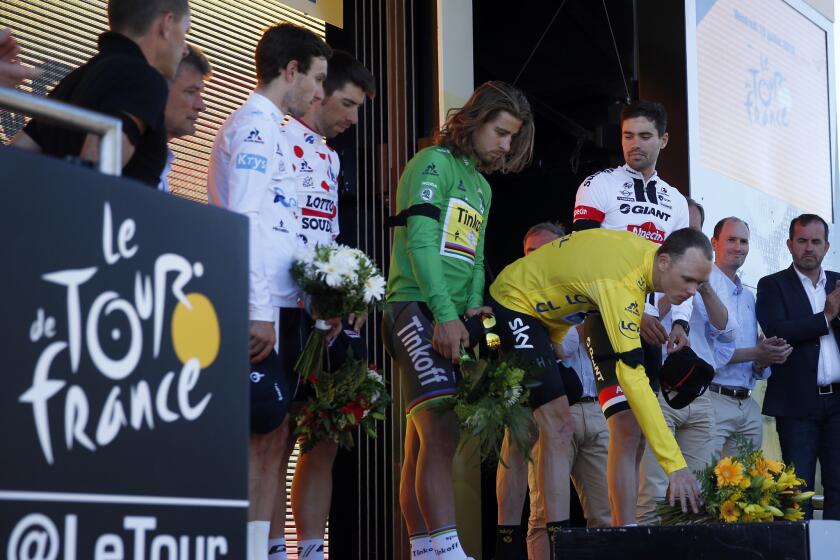 Chris Froome, wearing the overall leader's yellow jersey, lays flowers after observing a minute of silence to commemorate the victims of the Nice truck attack.