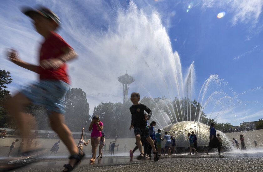 Children running amid water from a fountain