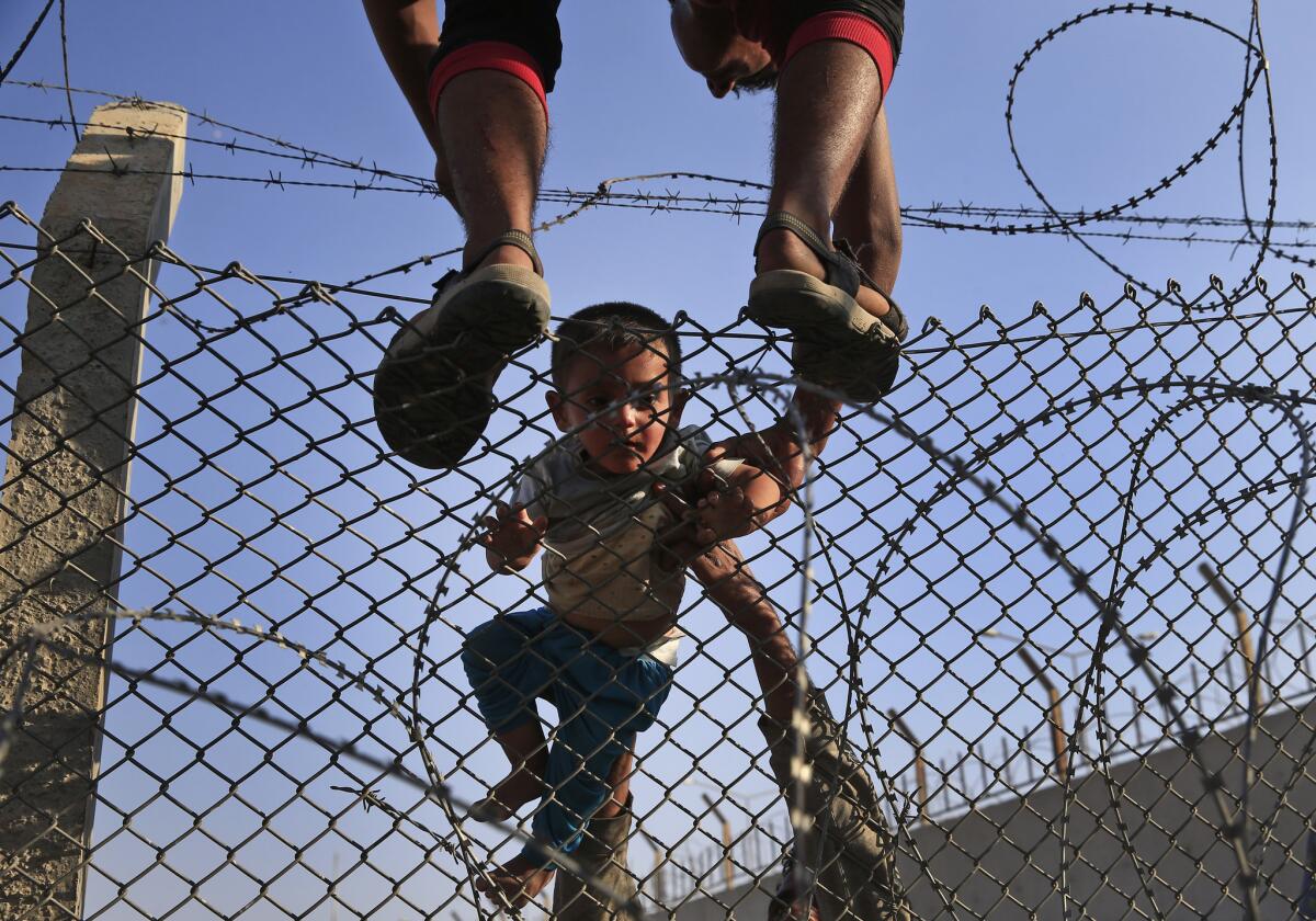 Syrian refugees carry a baby over the border fence into Turkey from Syria. Thousands of Syrians cut through a border fence and crossed over into Turkey, fleeing intense fighting in northern Syria between Kurdish fighters and jihadis.