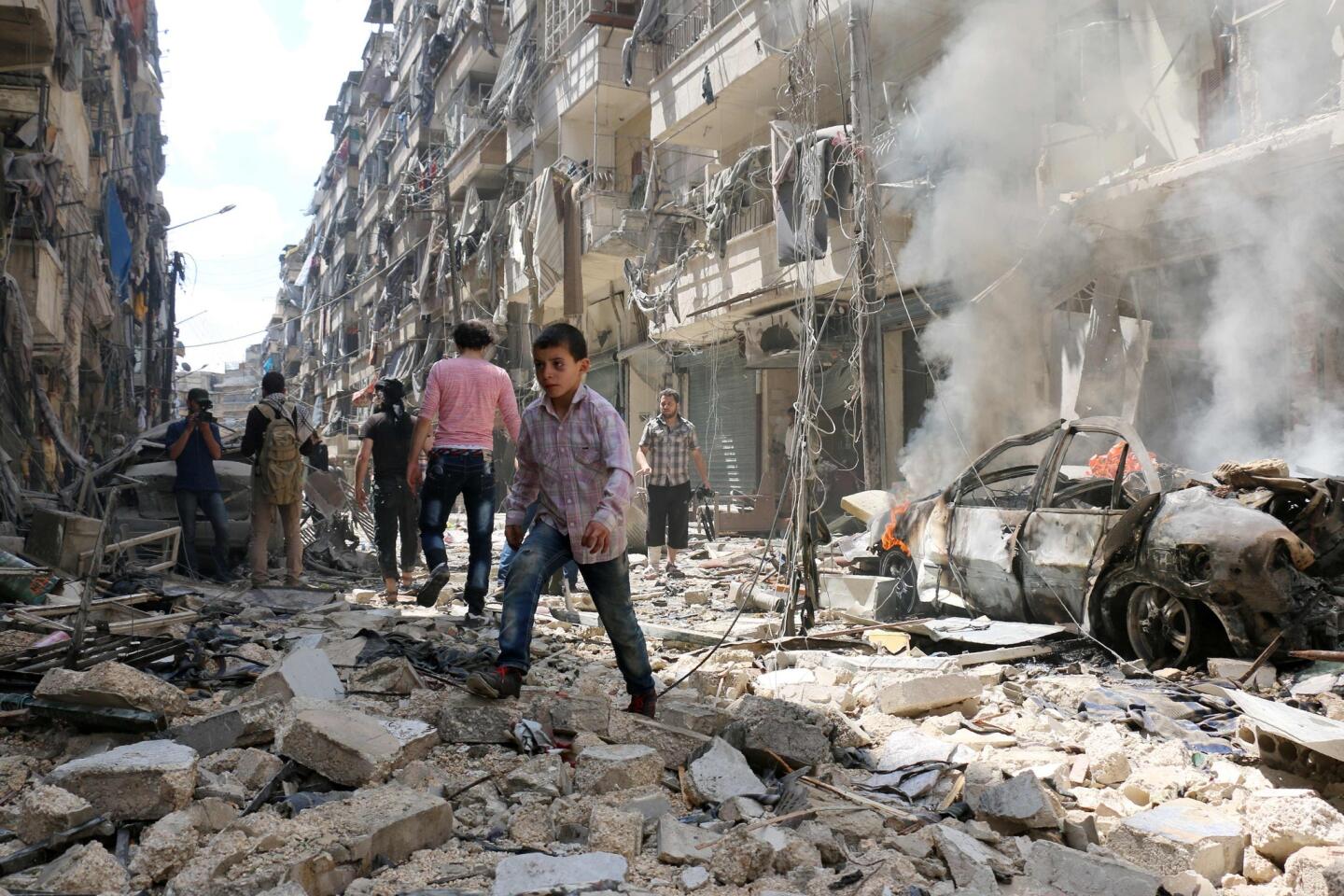 People walk amid the rubble of destroyed buildings following a reported air strike on the rebel-held neighbourhood of al-Kalasa in the northern Syrian city of Aleppo, on April 28, 2016.