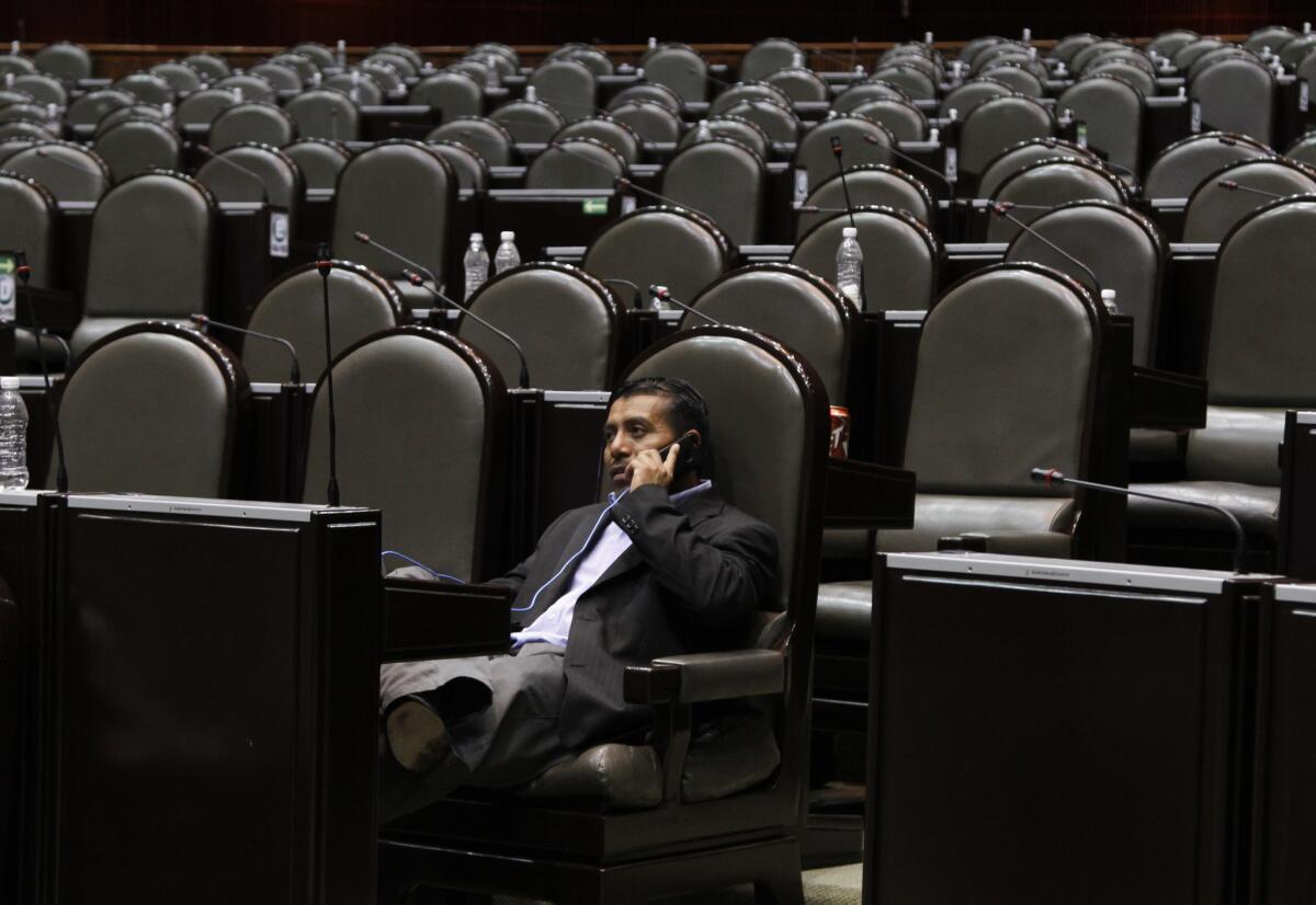 Opposition lawmaker Luis Martinez talks on his cellphone as dozens of leftist lawmakers take over the lower house late Wednesday trying unsuccessfully to block passage of the energy reform bill in Mexico City.
