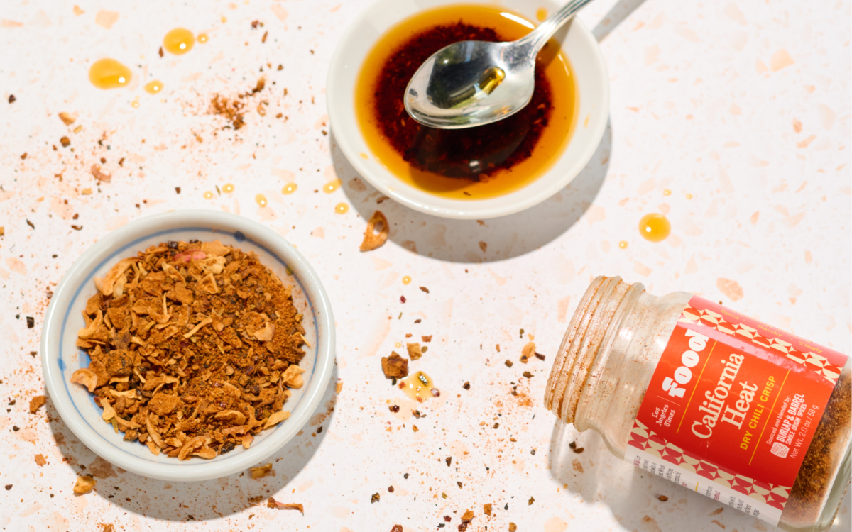 Small dishes of dried spice and oil with a spice bottle on its side on a countertop
