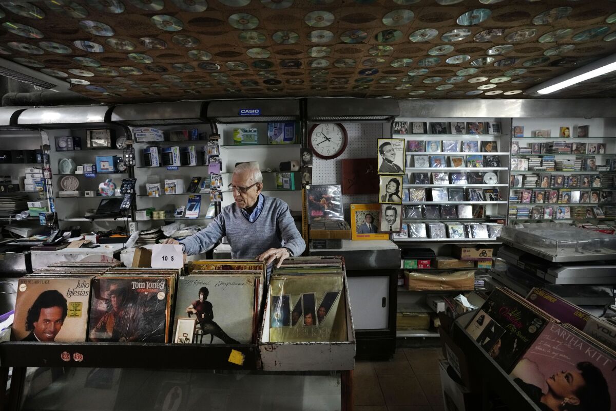 Michel Eid, 88, works in his music shop, on Hamra street, in Beirut, Lebanon, Wednesday, Jan. 12, 2022. From his small music shop, Eid witnessed the rise and fall of Lebanon through the changing fortunes of this famed boulevard for more than 60 years. Hamra Street once was home to the region's top movie theaters, shops selling international brands and cafes where intellectuals from around the Arab world gathered. (AP Photo/Hussein Malla)