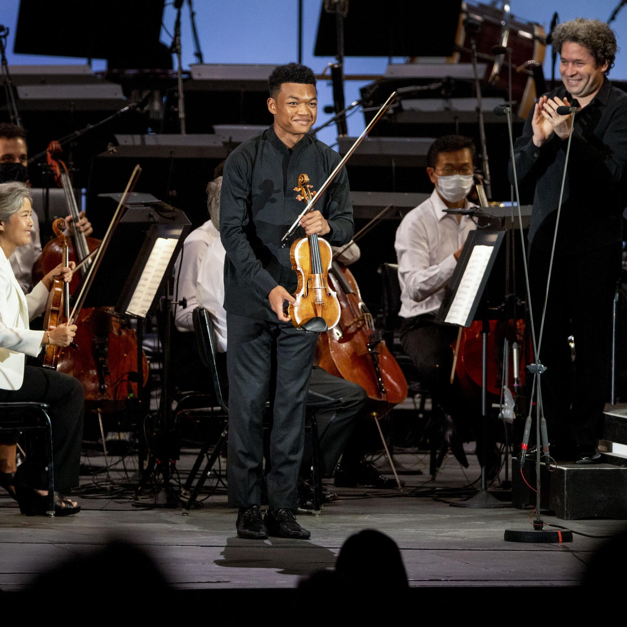 Violinist Randall Goosby takes bows as conductor Gustavo Dudamel claps at the L.A. Philharmonic's Hollywood Bowl.