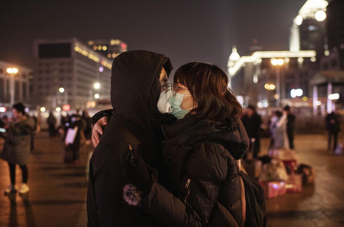 A Chinese couple, wearing their protective masks, kiss before saying goodbye at the Beijing railway station before the annual Spring Festival.