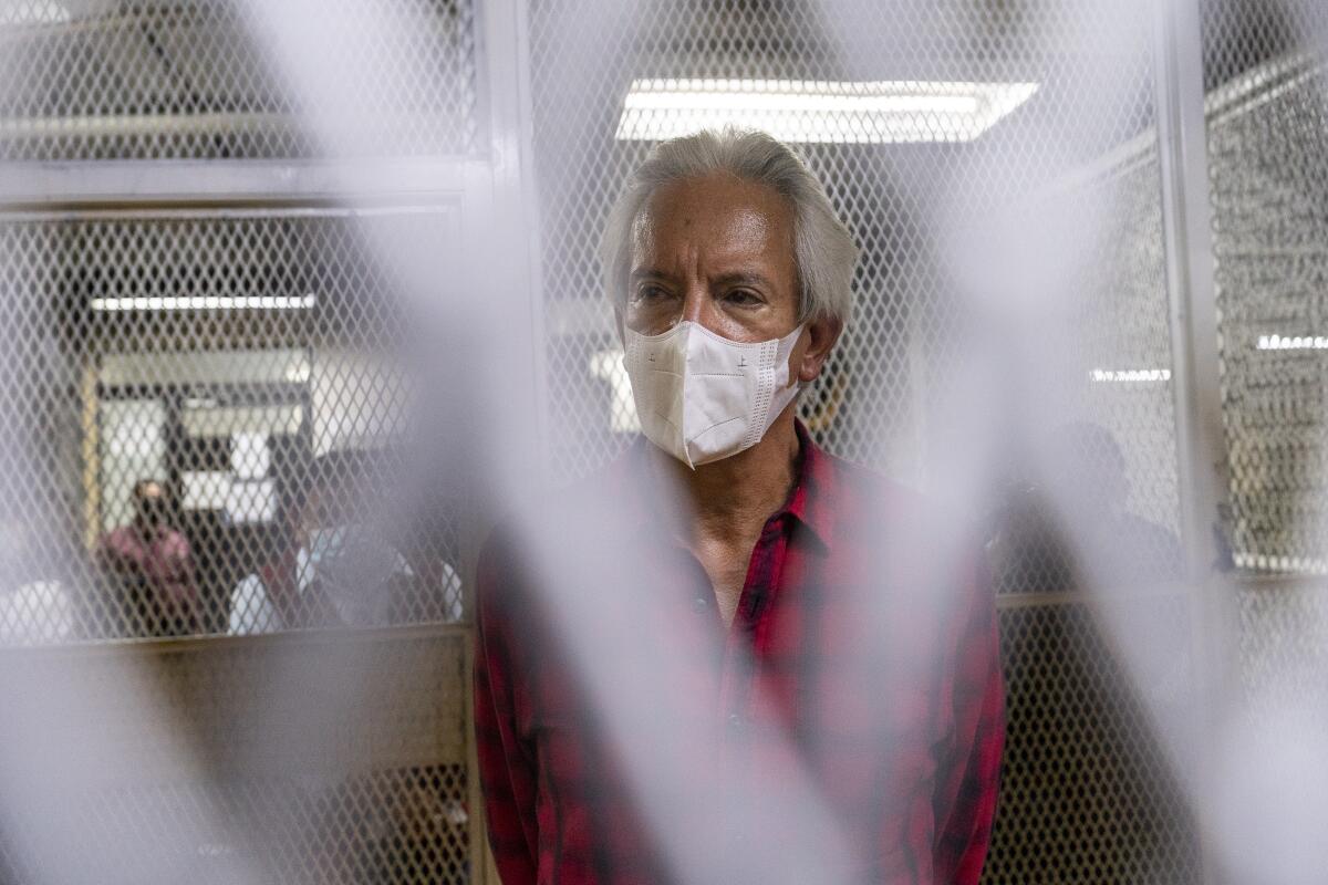 Journalist Jose Ruben Zamora stands inside a cell wearing a face mask